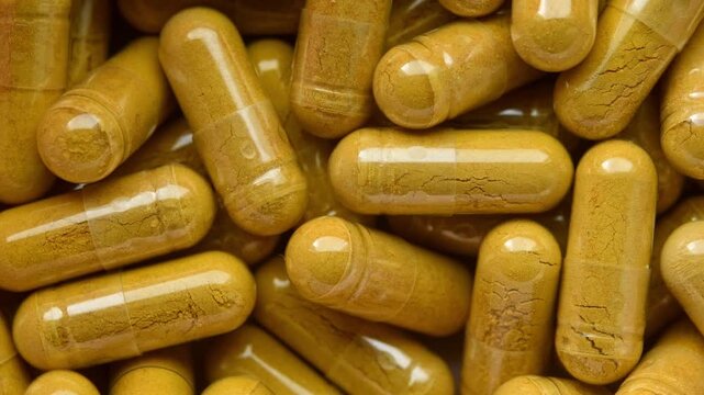 Slow rotation reveals close macro pattern of yellow herbal capsules for supplement, pharmacy, wellness, nutrition, healthcare
