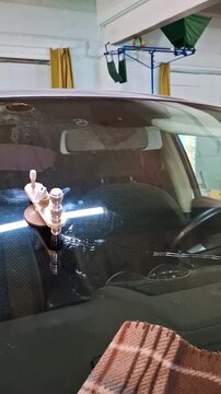 Professional car windshield repair process close up, mechanic using resin injector tool to fix a crack on automotive glass inside auto service.