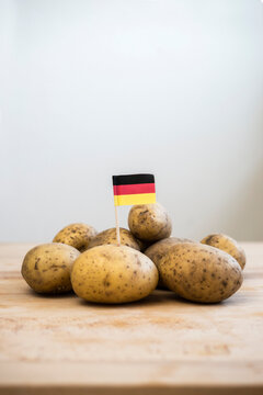 Row potatoes and small german little flag on wood