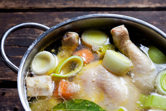 Cooking pot with raw corn-fed chicken, onion, herbs and greens , close-up