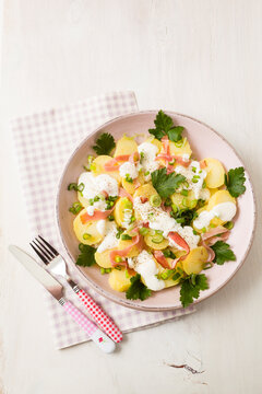 Potato salad garnished with spring onions, parsley and mayonnaise, close up