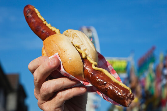 Man holding sausage with roll in hand