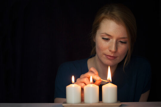 Portrait of young woman lighting candles