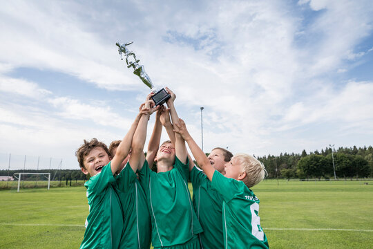 Young football players cheering with cup