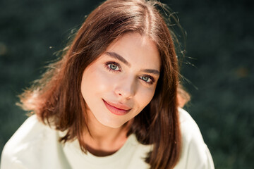 Obraz premium Young woman smiling portrait in natural light outdoors with soft expression and casual style