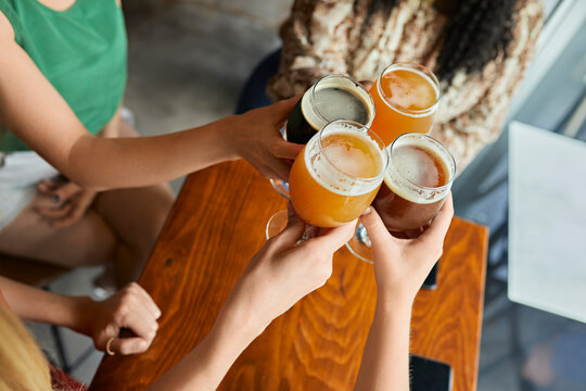 Female friends clinking craft beer glasses in a pub