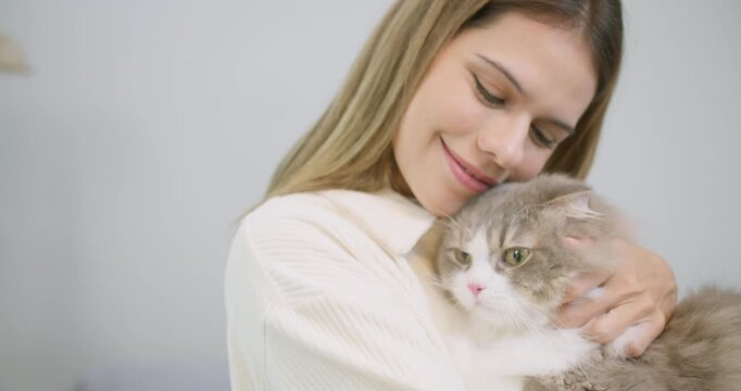 A loving pet owner gently cuddles her fluffy cat at home, finding comfort and showcasing the special bond and therapeutic companionship with her furry friend.