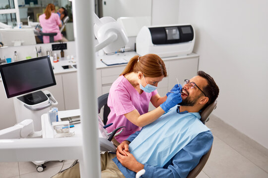 Dentist performing routine dental checkup on male patient