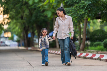 Obraz premium mother holding daughter's hand and walking together to school. First day of education.
