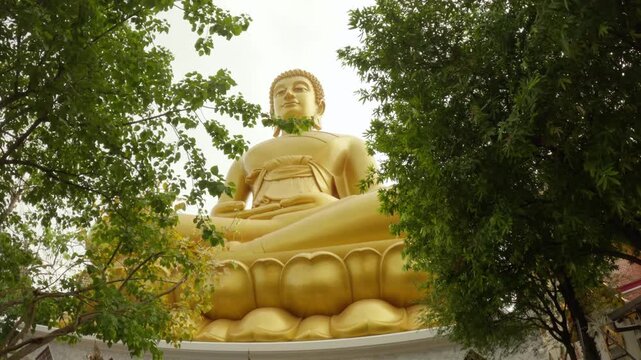 video footage highlights the magnificent golden Buddha statue at Wat Paknam Phasi Charoen in Bangkok. The colossal, serene statue is captured sitting in a meditative pose on a lotus base.
