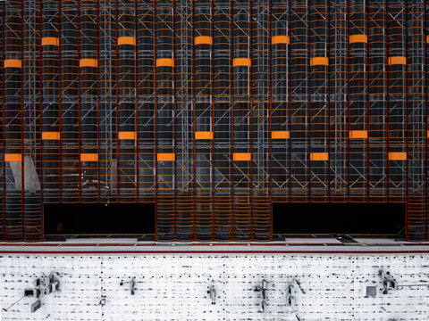 Aerial view of the modern rooftop featuring black mesh scaffolding with bright orange accents and a white textured base Warszawa, Wojewodztwo mazowieckie, Poland.