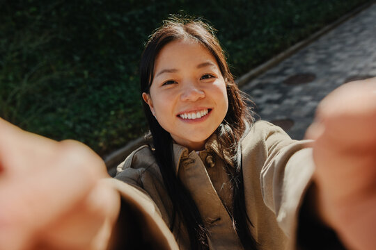 Smiling woman takes outdoor selfie on sunny street
