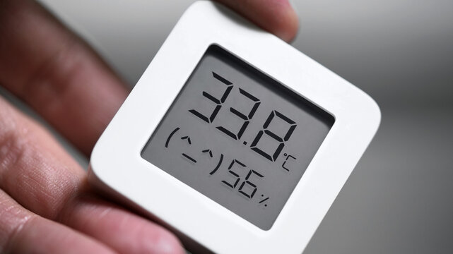 A modern electronic thermometer in action, showing high temperature and humidity in hot weather.