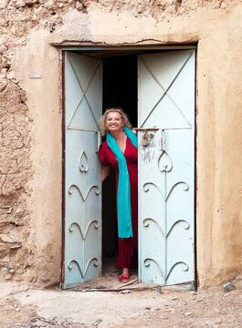 Smiling woman standing in the doorway of an abandoned house, Oman