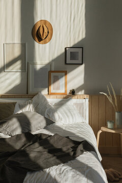 Cosy sunlit bedroom with natural shadows on a collection of assorted blank picture frames hanging over a double bed