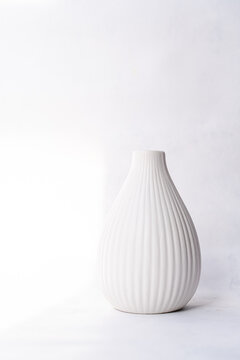 Close-up of a Minimalistic fluted white ceramic vase on a table on a sunny day