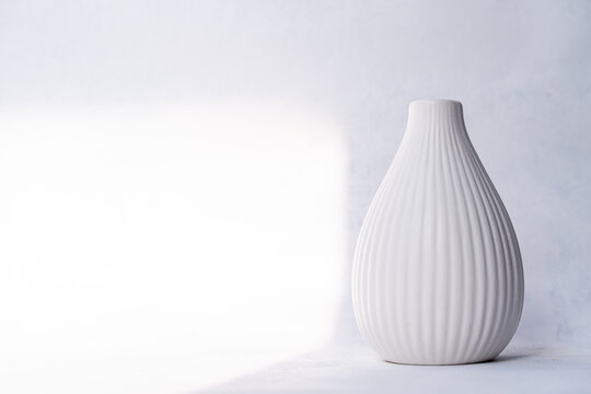 Close-up of a Minimalistic fluted white ceramic vase on a table on a sunny day