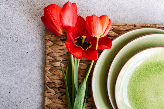 Overhead view of a rustic Spring place setting on a table with red tulips