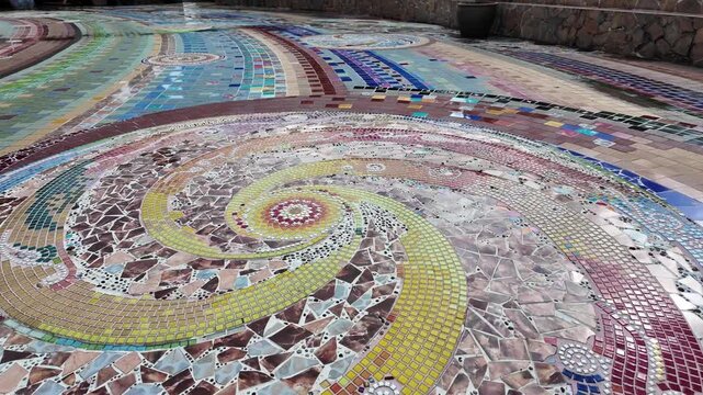Beautiful detailed shot of the colorful circular mosaic tiling on the ground of Wat Pha Sorn Kaew in Phetchabun, Thailand. Showcases intricate Buddhist art and pottery craftsmanship up close.