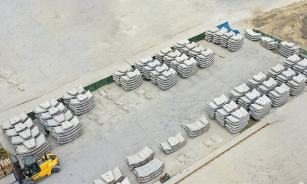Aerial view of stacks of curved concrete tunnel segments and a yellow forklift at an industrial storage site in Beylikduzu, Istanbul, Turkiye.