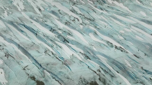 Drone aerial view of glacier crevasses revealing dramatic ice textures and formations, frozen patterns, and moraine in a remote polar landscape.