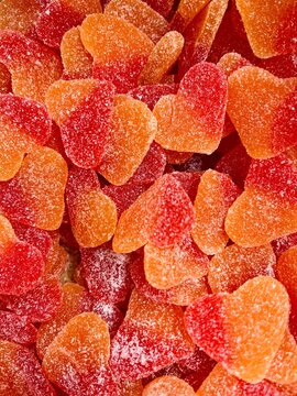 Full frame close-up of a stack of gummy peach hearts with a sugar coating