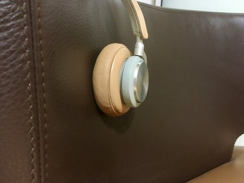 Close-up of headphones on the arm of a  brown leather sofa