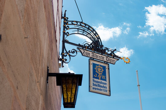 Nuremberg, Germany- May 2, 2025: Traditional German wrought iron hanging sign (Nasenschild) for Zum Albrecht D&uuml;rer restaurant serving traditional Augustiner Br&auml;u M&uuml;nchen beer