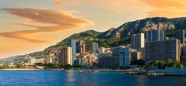 scenic cityscape of embarkment of Monte Carlo city in Monaco with blue sea water bay and amazing tall buildungs and houses along the coast. Urban mideterranean landscape with mountains and cloudy sky.