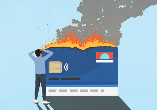 Shocked man watching large credit card burn against blue background