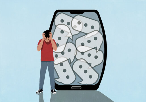 Overwhelmed boy standing with head in hands next to text message speech bubbles on device screen