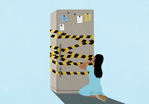 Girl kneeling with head in hands in front of refrigerator wrapped in barricade tape