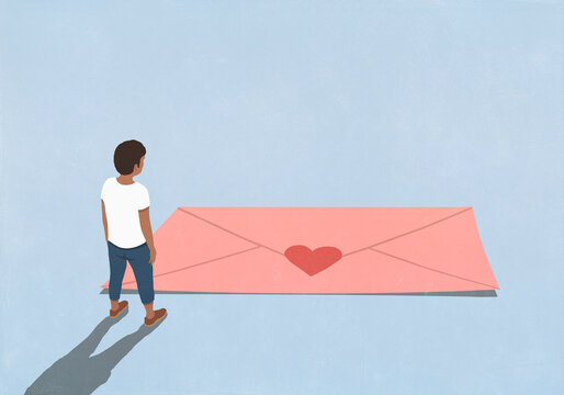 Man looking down at large pink envelope with red heart shape sticker