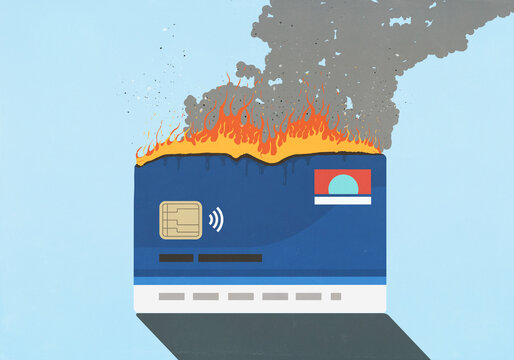 Credit card burning and smoking against blue background