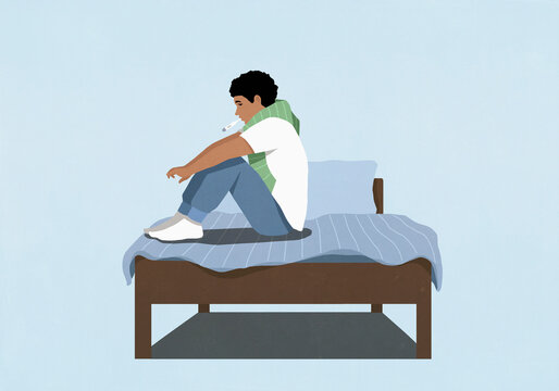 Man with fever using thermometer on bed