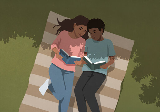 High angle view of serene young couple reading books on blanket under shady tree shadow