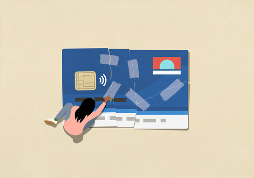 View from above of woman mending ripped credit card with adhesive tape
