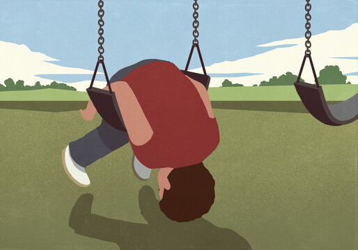 Boy folded over swing on playground