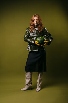 Portrait of a fashionable woman  with long red hair holding a watermelon