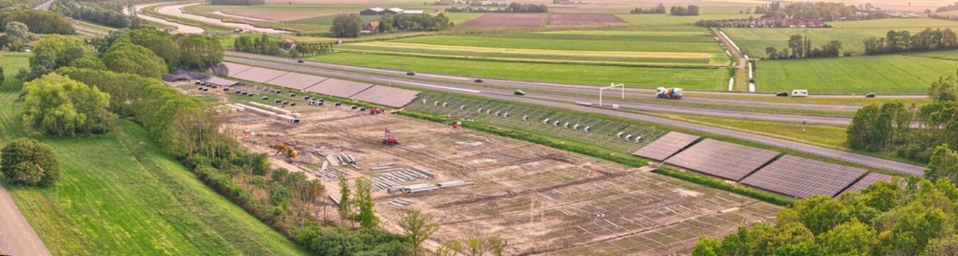 Aerial view of the construction site of a solar park along the A7 highway embankment near the Afsluitdijk sea protection dike Den Oever, North Holland, Netherlands.