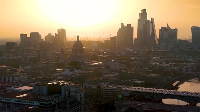 Establishing aerial view of the skyline of London, England, with St. Pauls Cathedral and the City during a golden summer sunrise