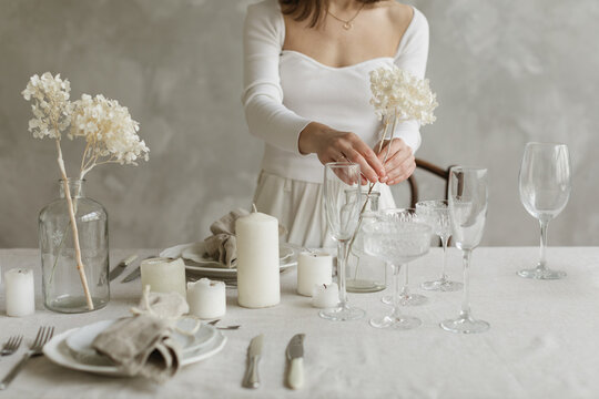 Close-up of a woman standing at a dining table setting the table for a dinner party