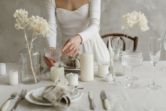 Close-up of a woman standing at a dining table setting the table for an elegant dinner party