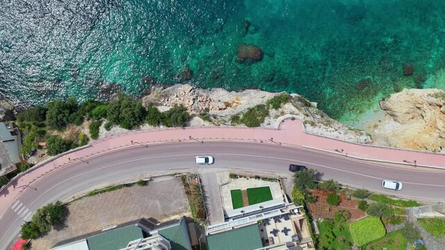 Top-down aerial video showing a winding seaside road and the blue waters of Ionian sea in southern Vlora, Albania.