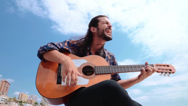 Traditional Spanish musician singing on a sunny day with clouds background. Looking up shot.