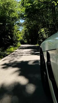 convertible car in sunny nature on a bright summer day. wide angle pursuit shot - vertical video for reels and story
