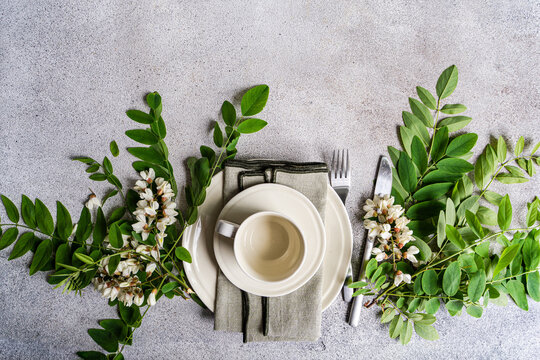 Overhead view of a Spring table setting decorated with fresh Acacia flowers on a concrete table