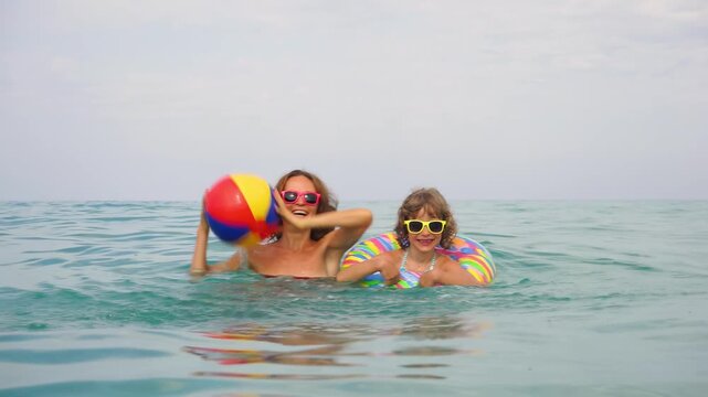 A happy child with mother having fun on beach during summer holidays. Slow motion