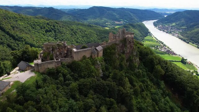 Aggstein Castle Austria Aerial 4K. Drone cinematic flight over imposing medieval fortress ruins high up on green hills. Scenic Danube river panorama in Wachau valley landscape. Summer travel