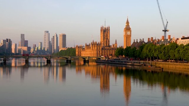 Beautiful summer sunrise view of the Westminster Bridge and Palace with Big Ben clocktower in London, England, with reflections in the River Thames